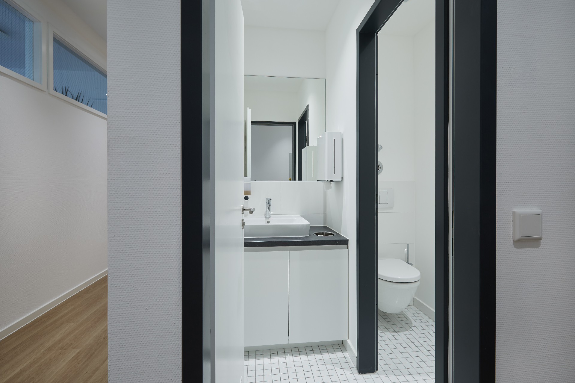Moderne Sanitäranlage mit weißem Mosaik und schwarzer Akzentkante