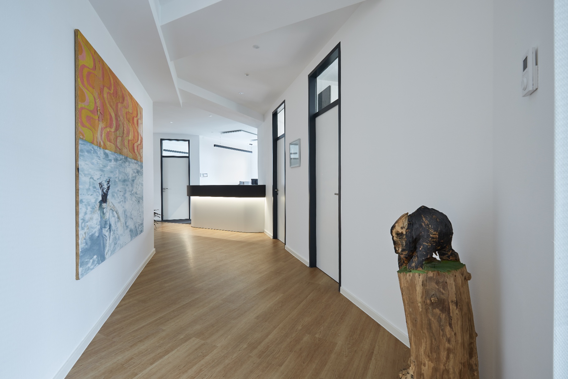 Heller Flur mit Kunst, Skulptur und Empfangstresen
