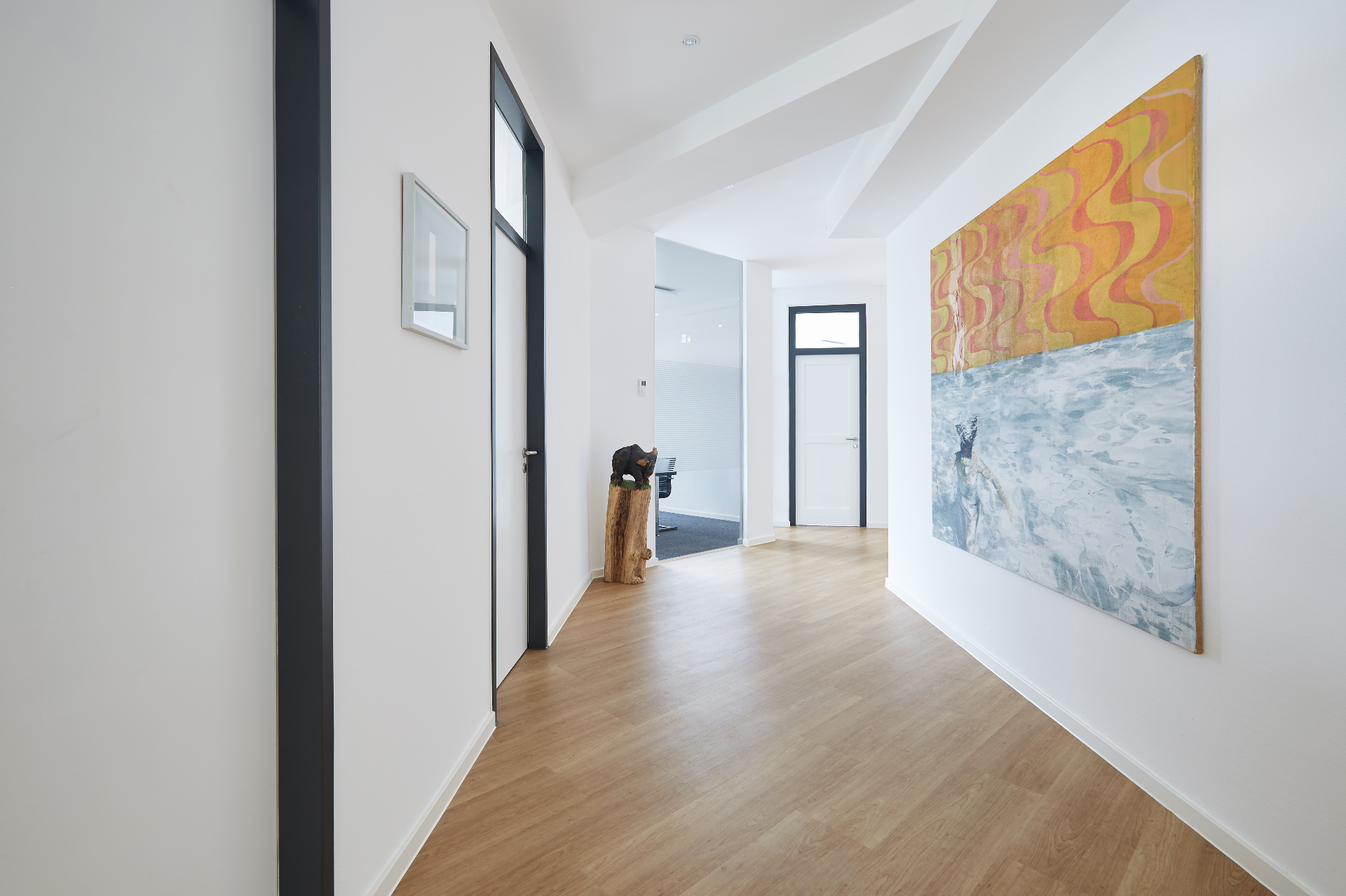 Korridor mit Kunstwerk und Blick in das Besprechungszimmer