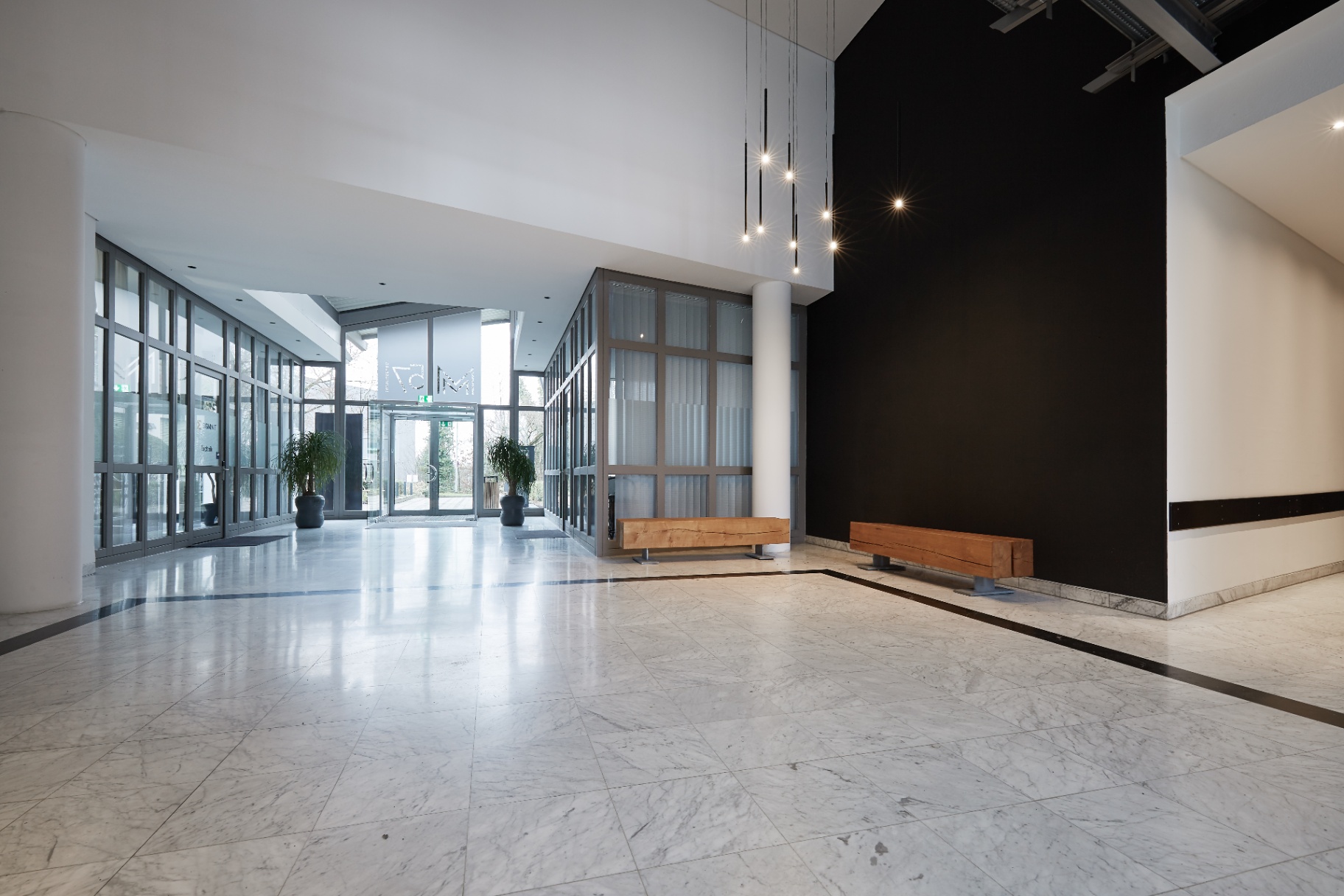 Großzügiges Foyer mit Marmorboden, Eichenbänken und Lichtinstallation