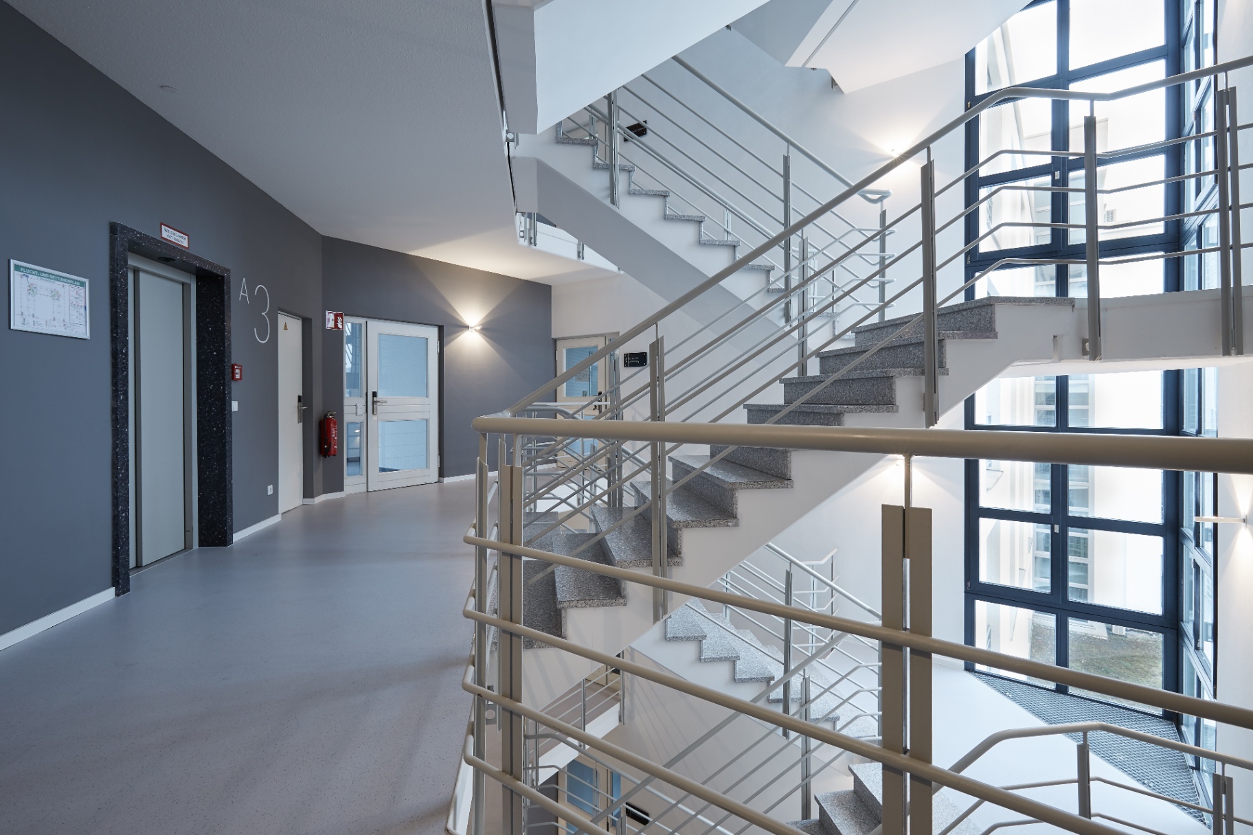 Repräsentatives Treppenhaus mit Glasfassade und Aufzugzugang